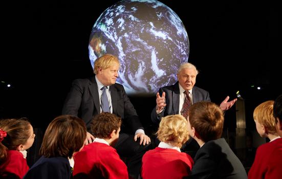 The Prime Minister and Sir David Attenborough sitting in front a picture of the globe, answering questions from pupils from Barnes Primary School and John Betts Primary School