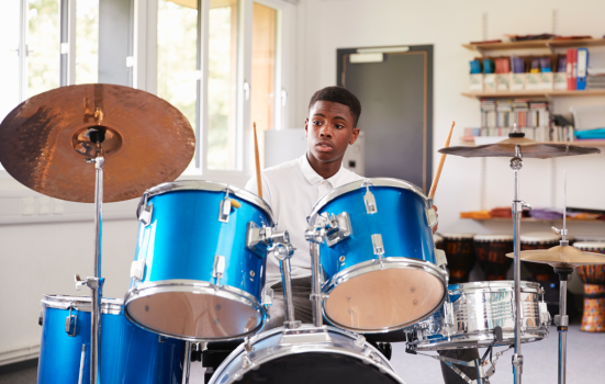 A boy sitting and playing the drums