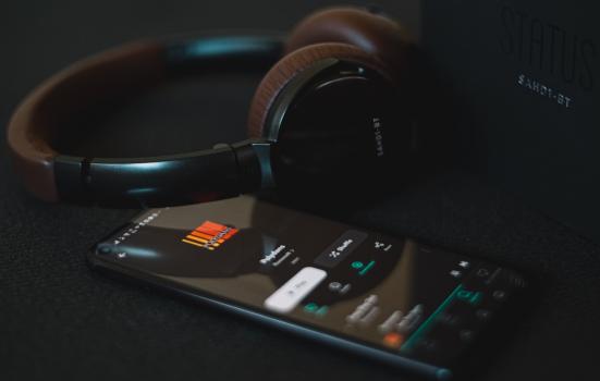 a phone streams music next to a pair of headphones