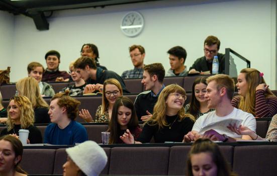 Students sitting in a lecture theatre chatting
