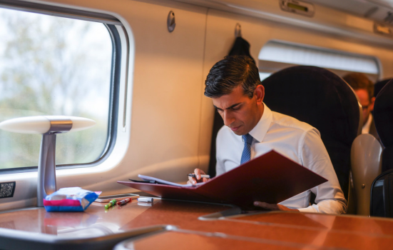 Prime Minister Rishi Sunak sat on a train reading documents