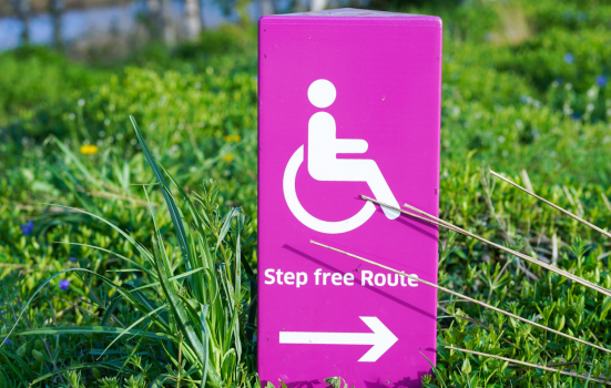 a sign with a logo of a person in a wheelchair, signalling access to a step free route