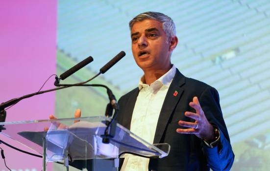 Sadiq Khan speaking at an event wearing a white collared shirt and dark suit jacket