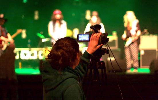 A young person recording a music performance using video equipment