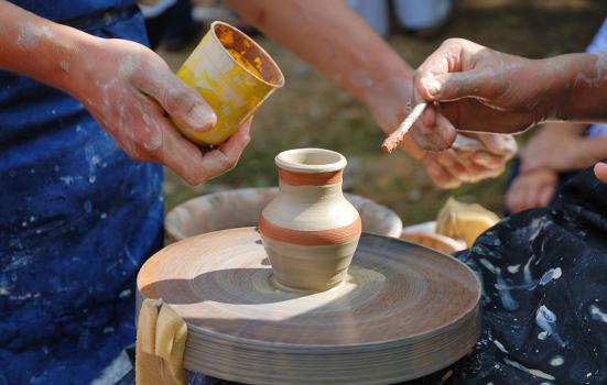 Two people creating a pot on a potter's wheel