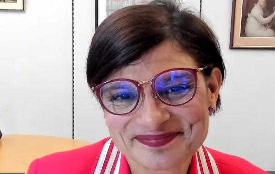 A screen shot of Shadow Culture Secretary Thangam Debbonaire in a Zoom call. She has short dark hair and wears a red jacket with matching glasses