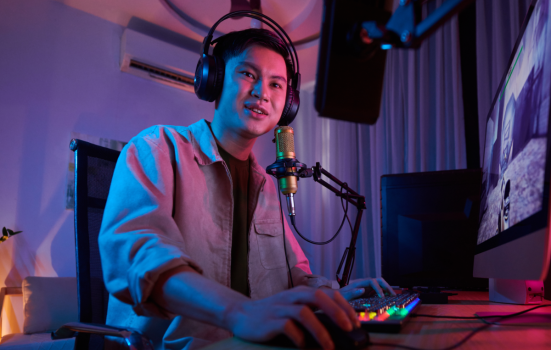 voice over artist working in a studio. image depicts a man wearing headphones, speaking into a microphone while doing work on his computer