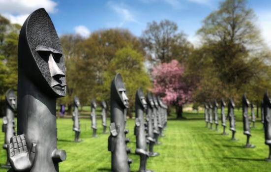 A row of black sculptures on a grass lawn