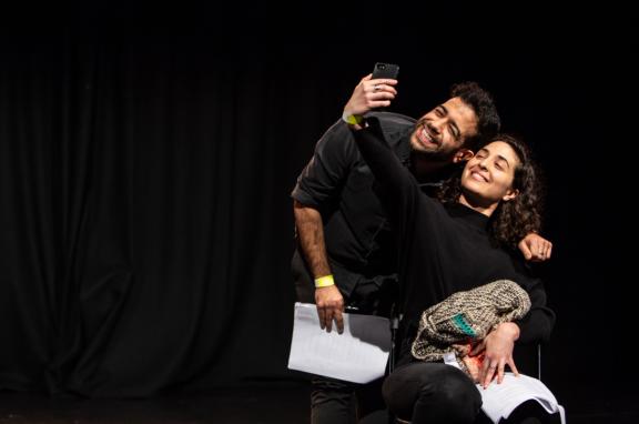 Two actors perform on stage, smiling taking a selfie