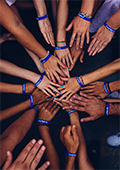 the bare arms of a group of mixed-race people stretching out hands on top of each other in a circle
